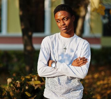 Young man standing with arms crossed outdoors.