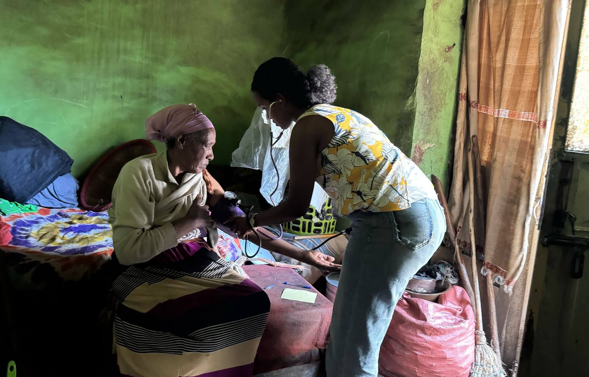 Person assisting elderly woman on the bed.