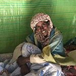 Smiling woman sitting inside a green tent.