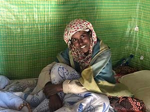 Smiling woman sitting inside a green tent.
