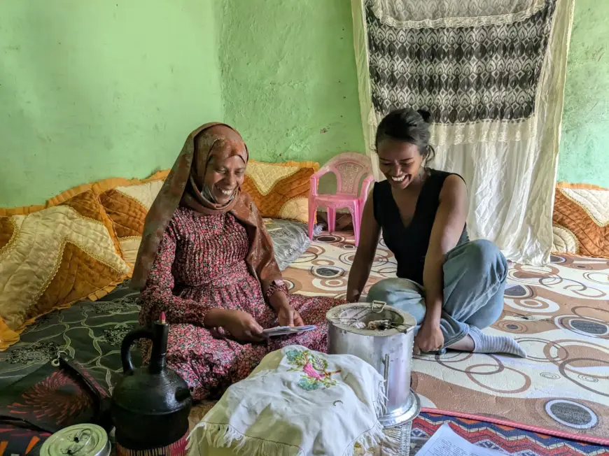 Two women sitting and smiling indoors.