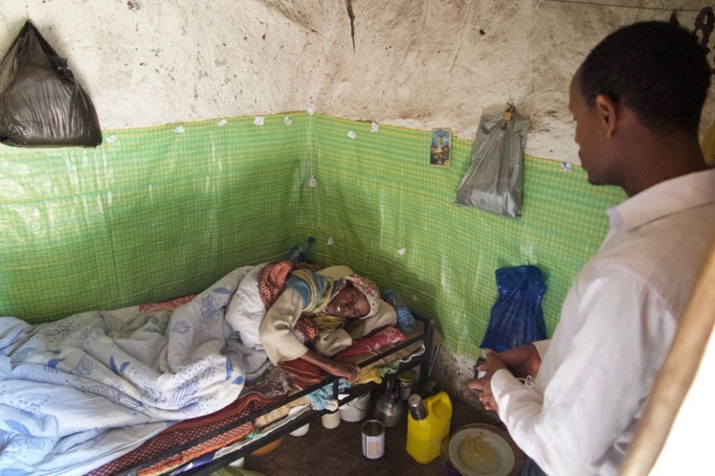 Man visiting person in small, modest room.