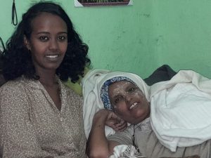 Two women sitting together, one lying down.