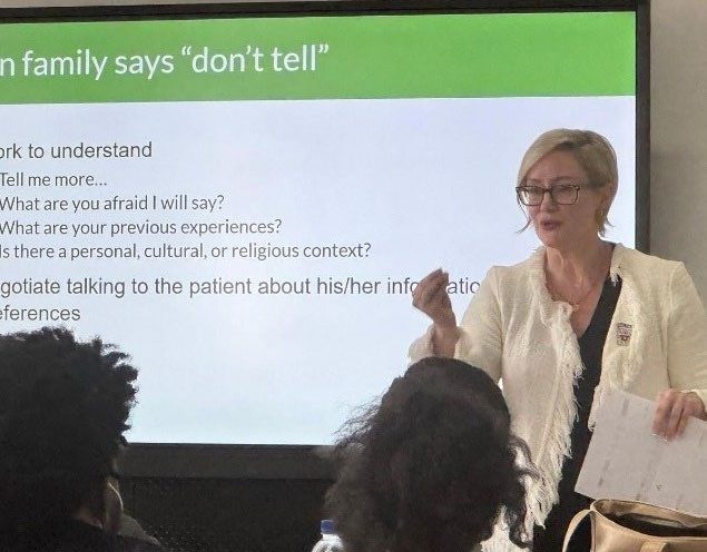 Woman presenting to an audience with slides.