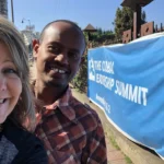 Two people smiling at leadership summit sign.