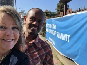 Two people smiling at leadership summit sign.
