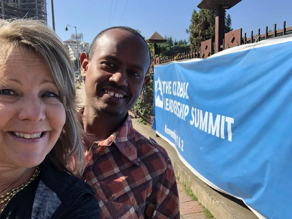 Two people smiling at leadership summit sign.