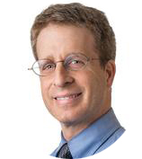 Man smiling, wearing glasses and blue shirt.