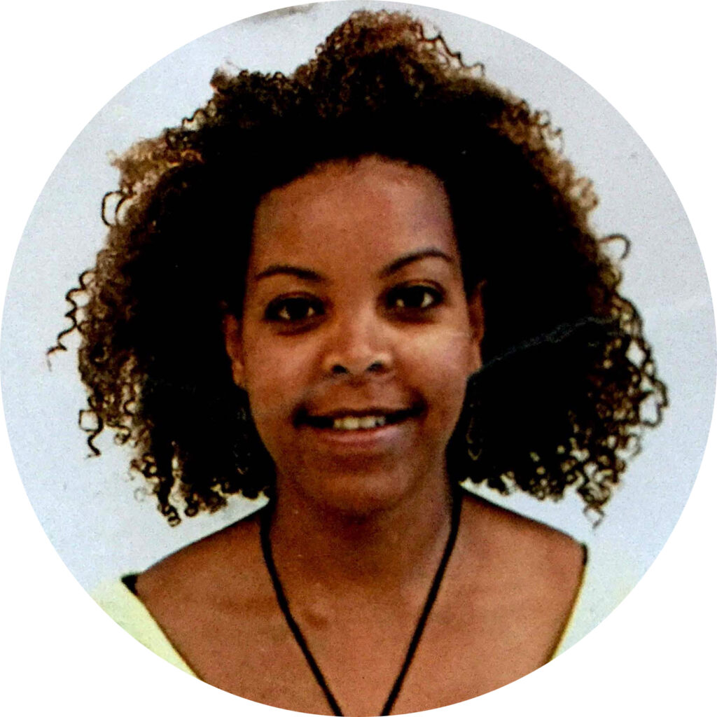 Young person smiling with curly hair.